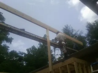 Carpenter setting a ridge beam over a new addition frame — Ice Dam Removal by Roofing Brothers in Tylertown
