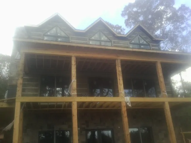 Dormers and porch framing on a large log home under construction — Roof Coating work by our crew in Tylertown